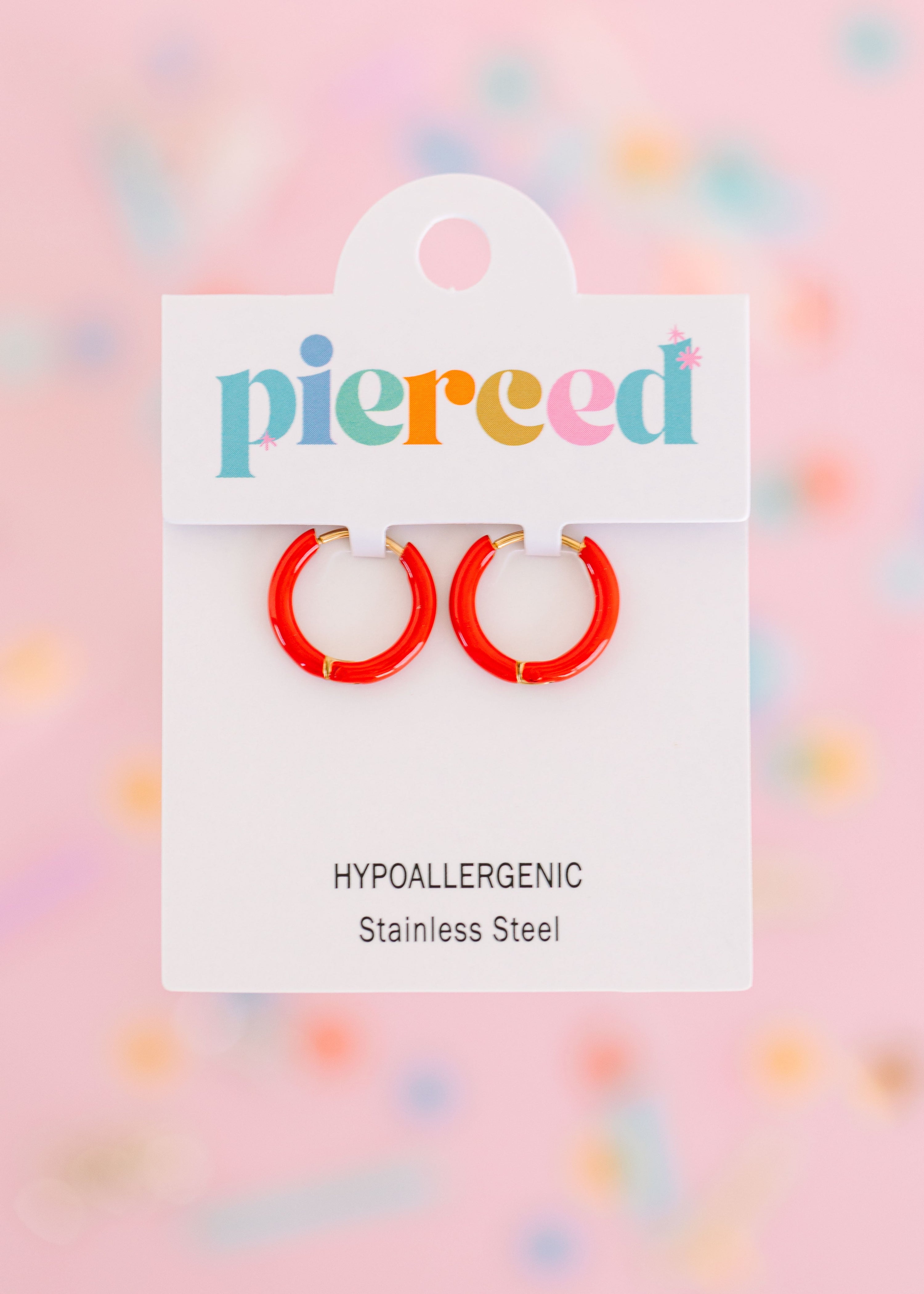 Red hoop earrings on their packaging card with a colorful blurred background