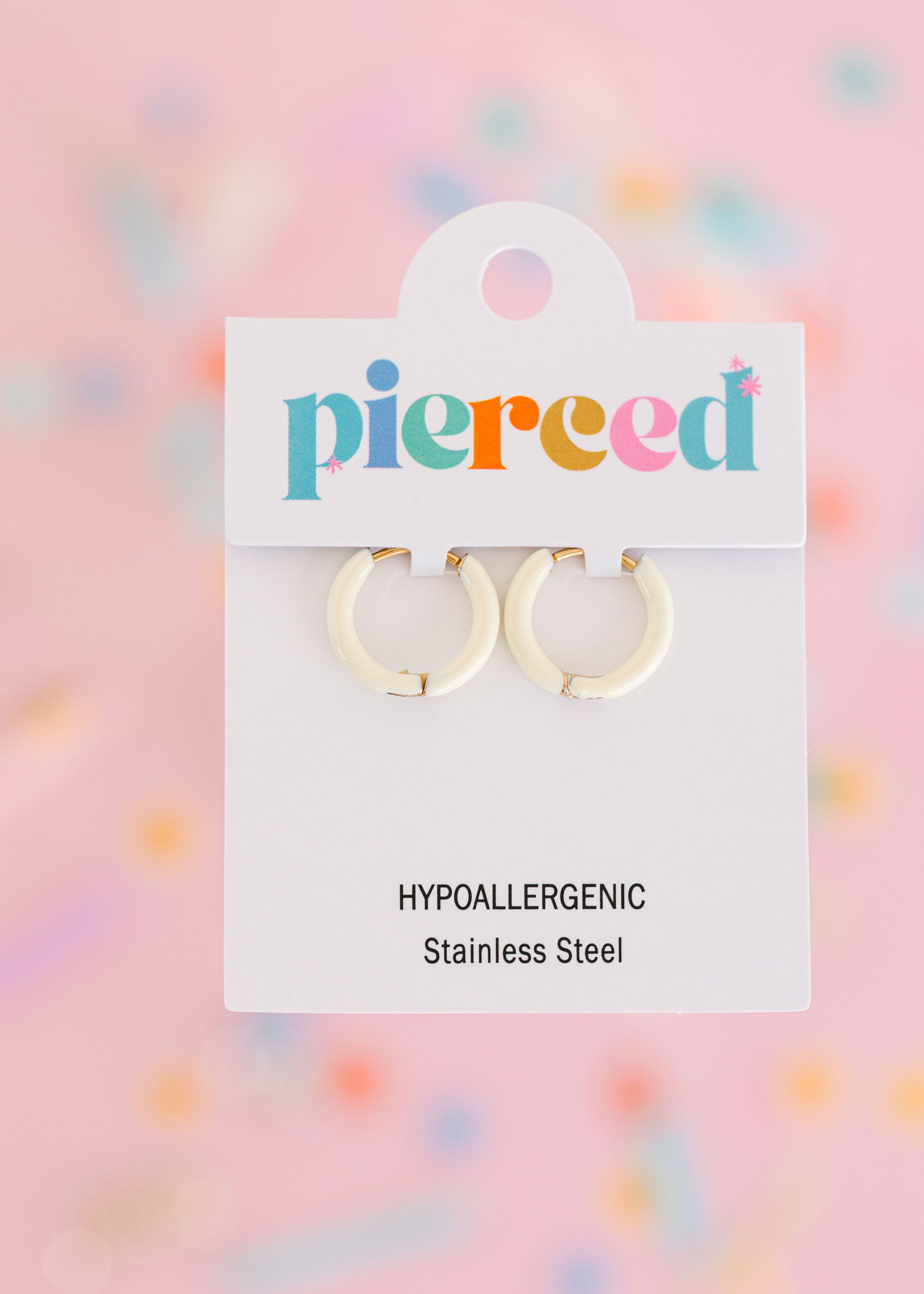 Barely Yellow hoop earrings on their packaging card with a colorful blurred background