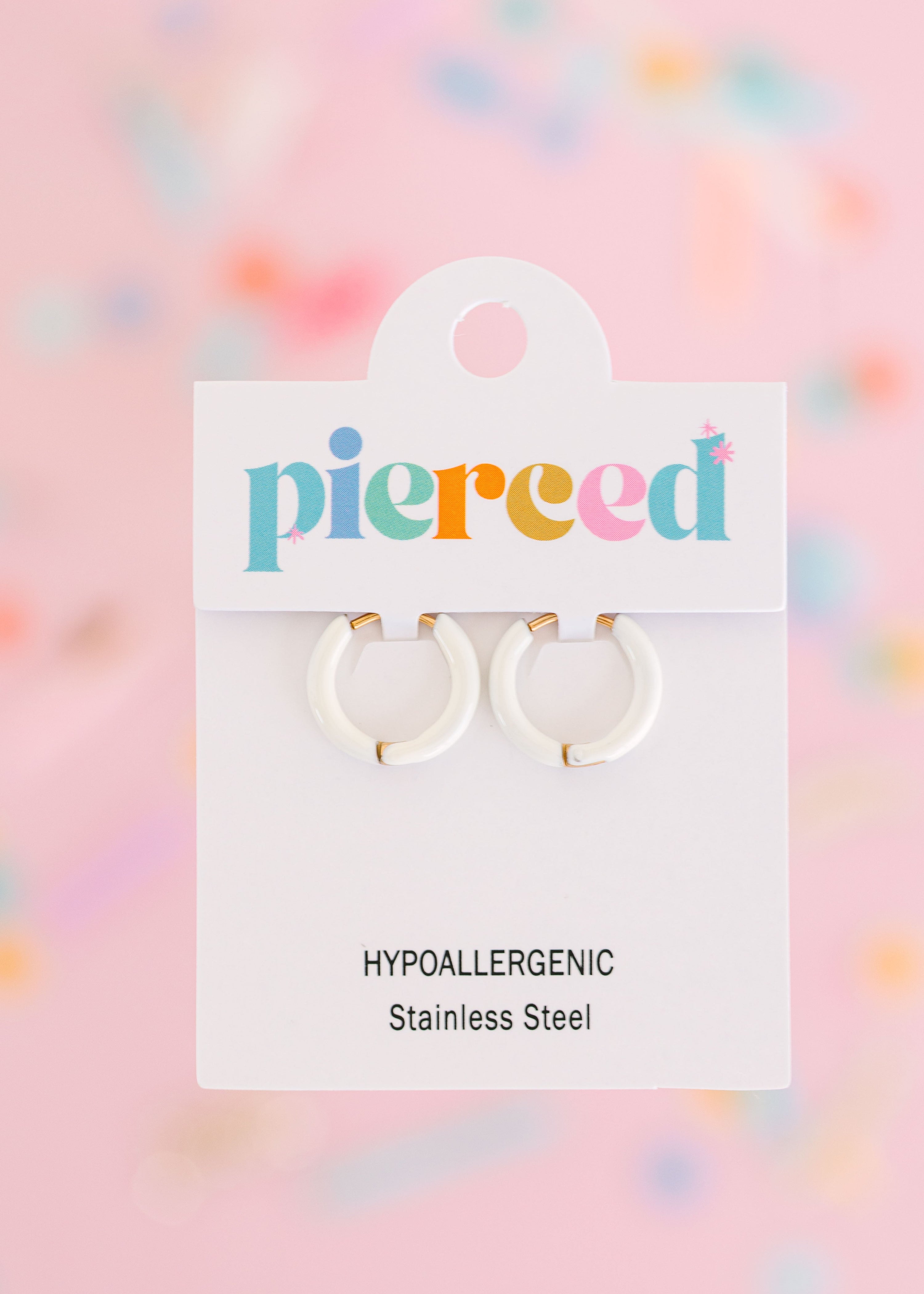 Cream hoop earrings on their packaging card with a colorful blurred background