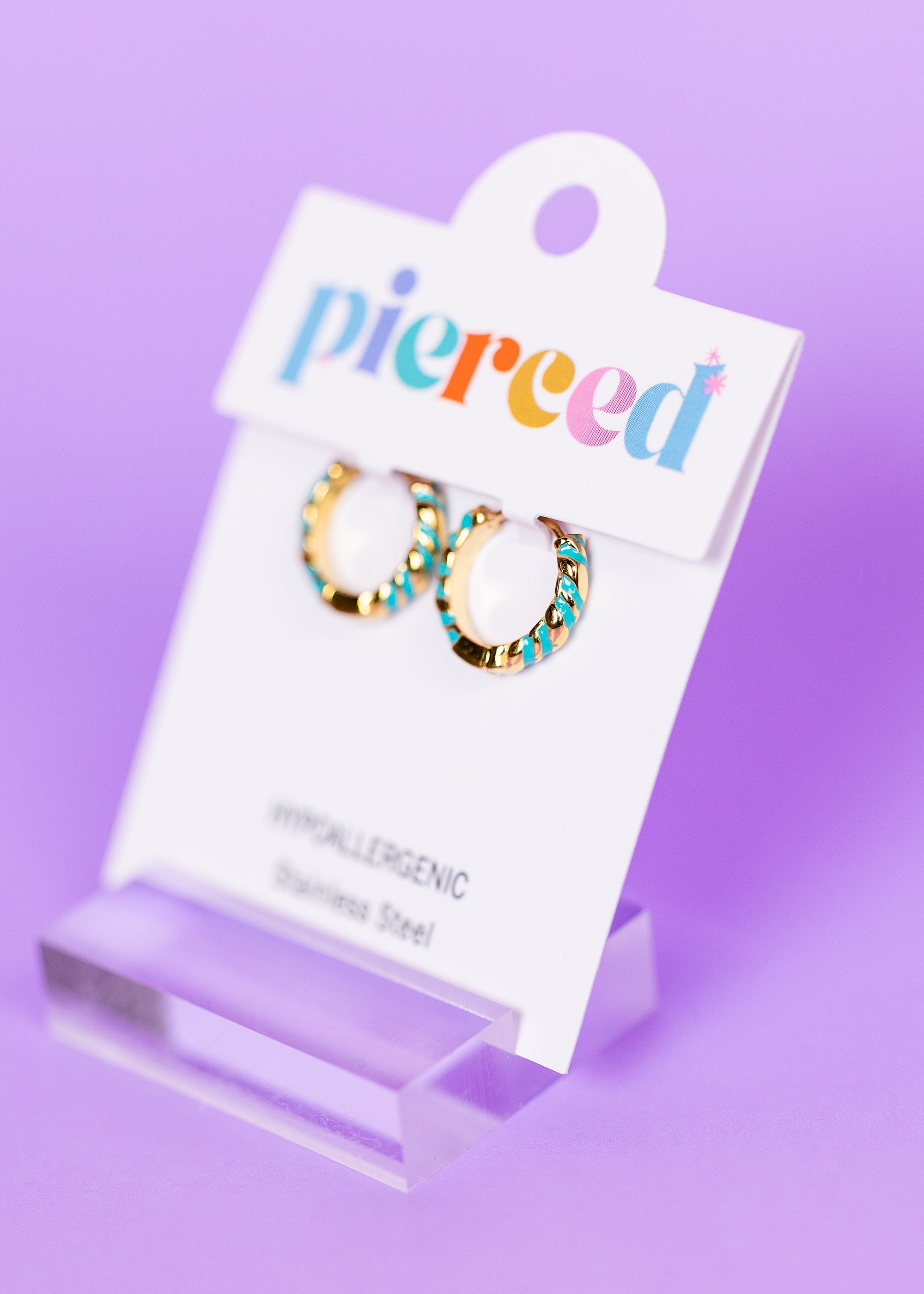 Hoop earrings on a 'pierced' card with a colorful 'pierced' text against a purple background