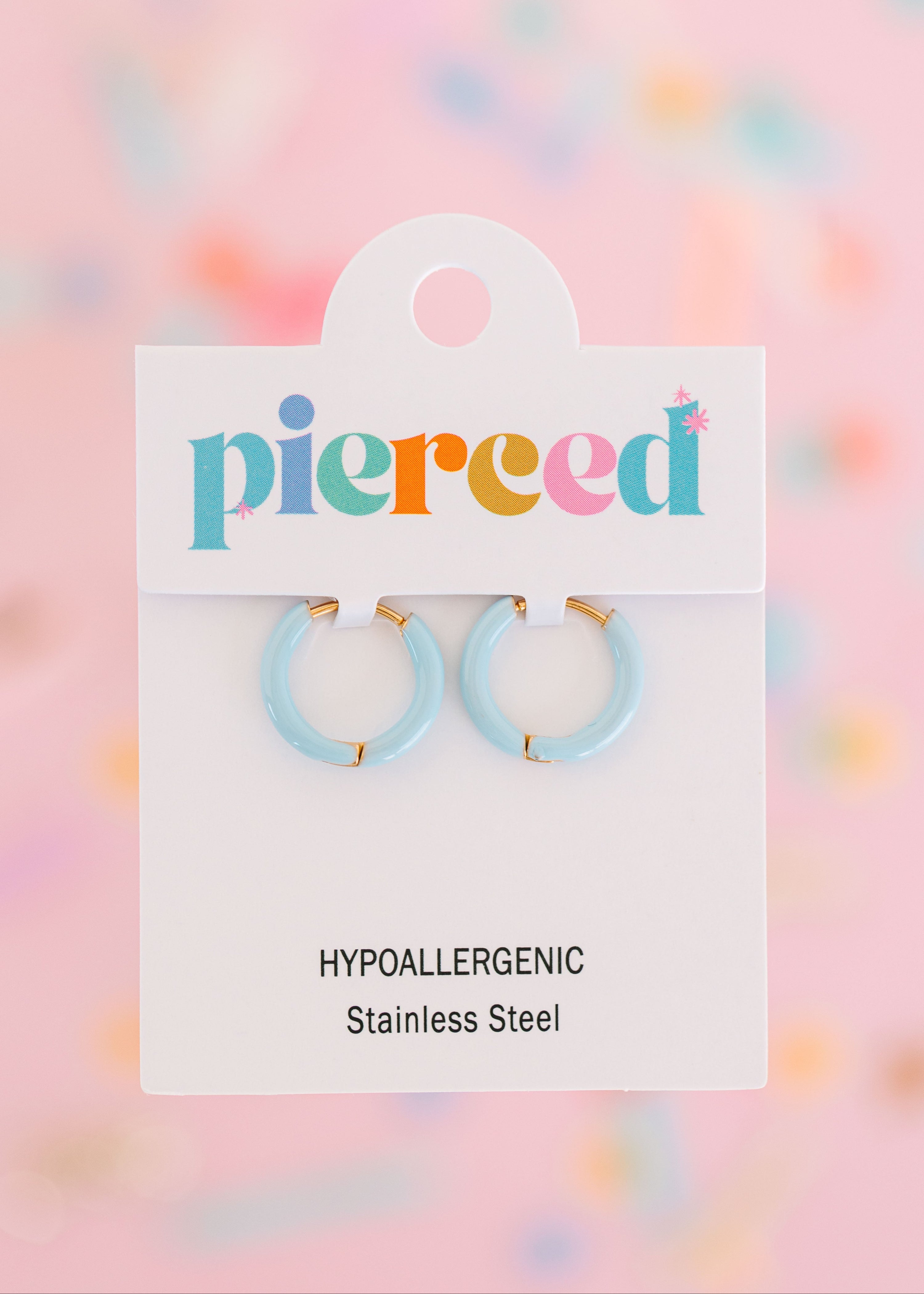 Baby blue hoop earrings on their packaging card with a colorful blurred background
