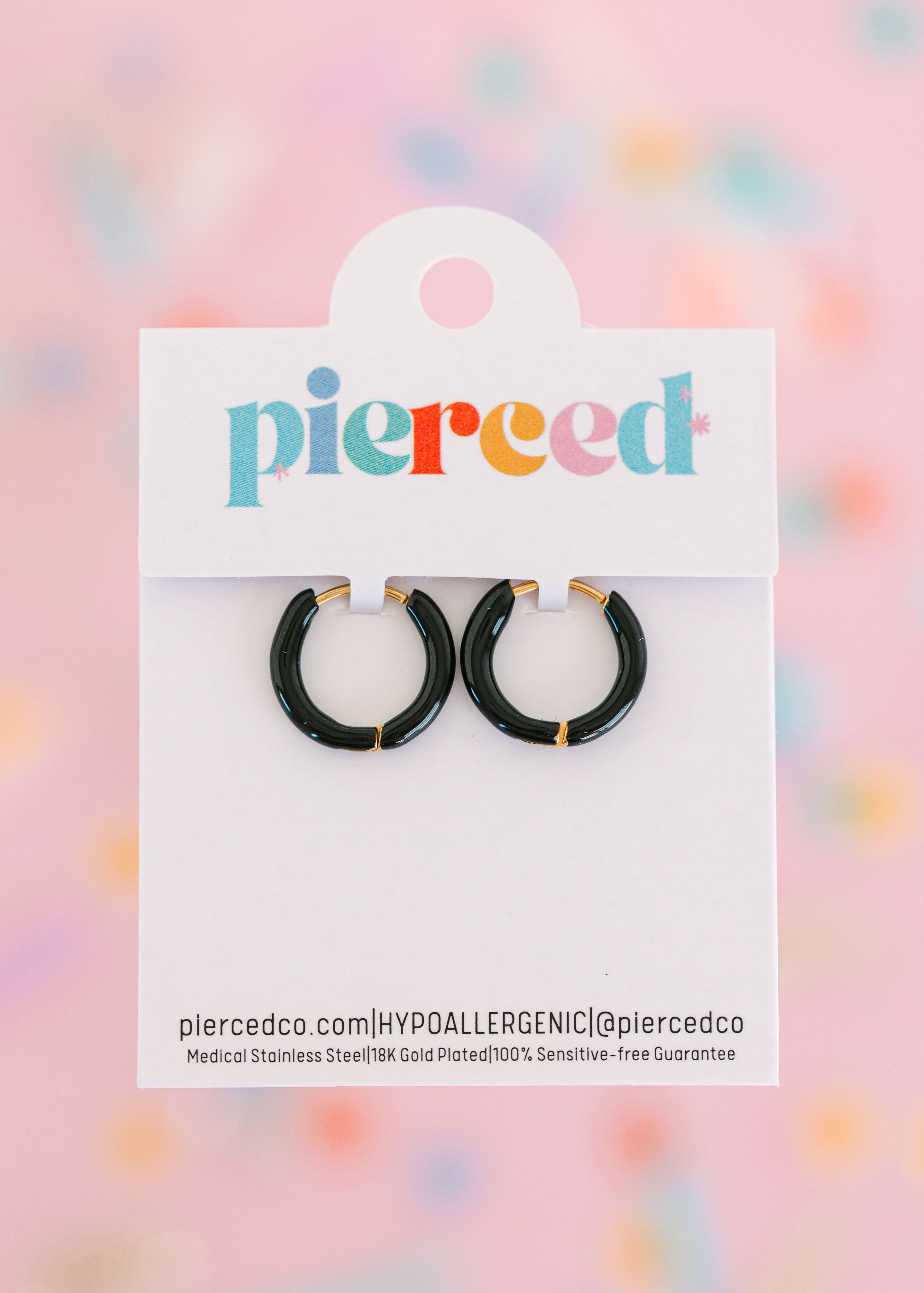 Black hoop earrings on their packaging card with a colorful blurred background
