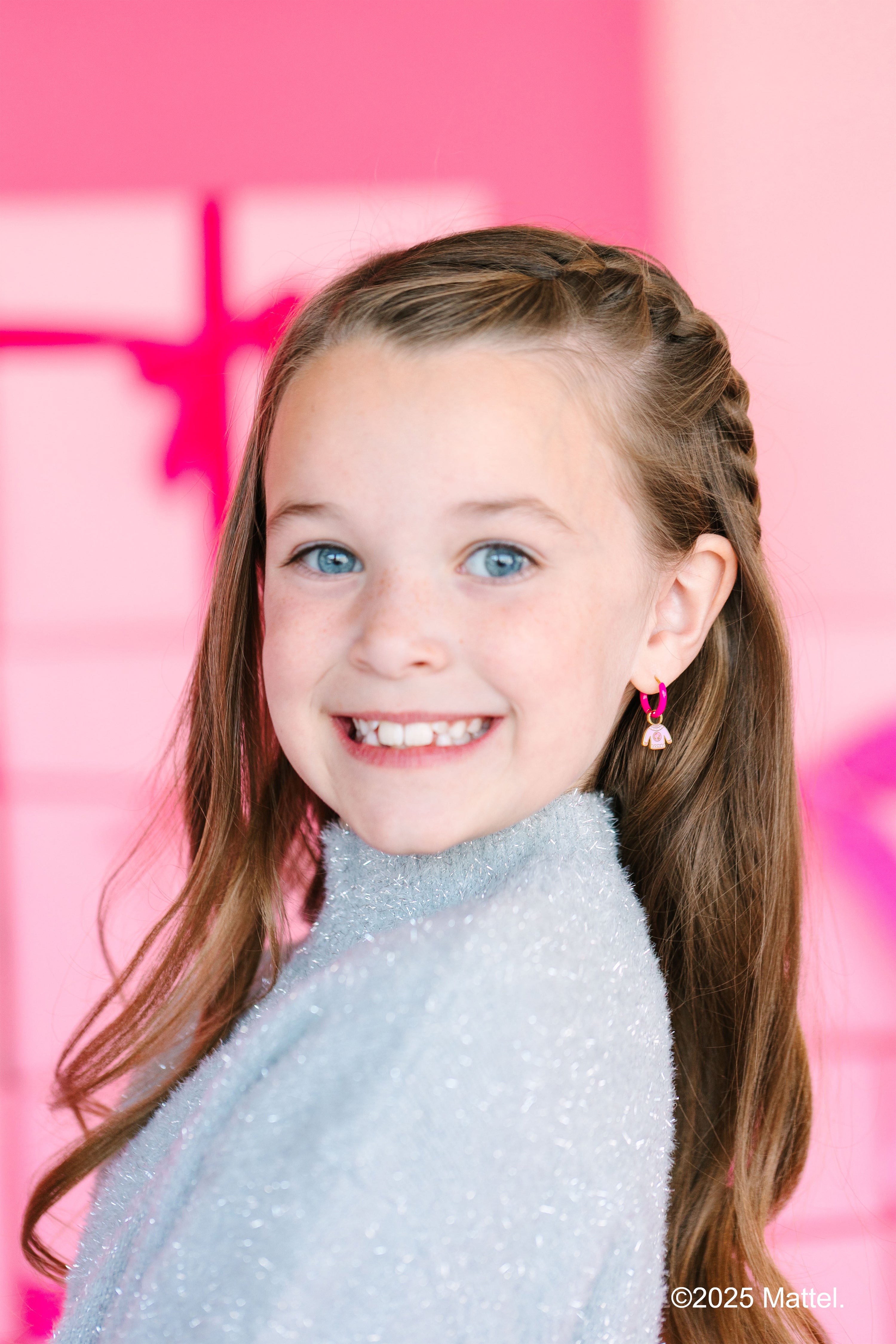 Young girl with braided hair against a pink background