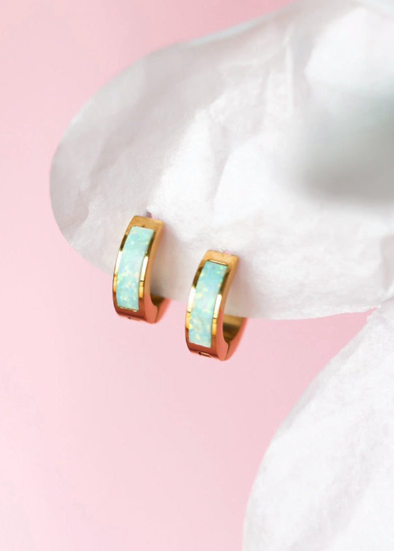 Ocean blue opal huggies on white petal background