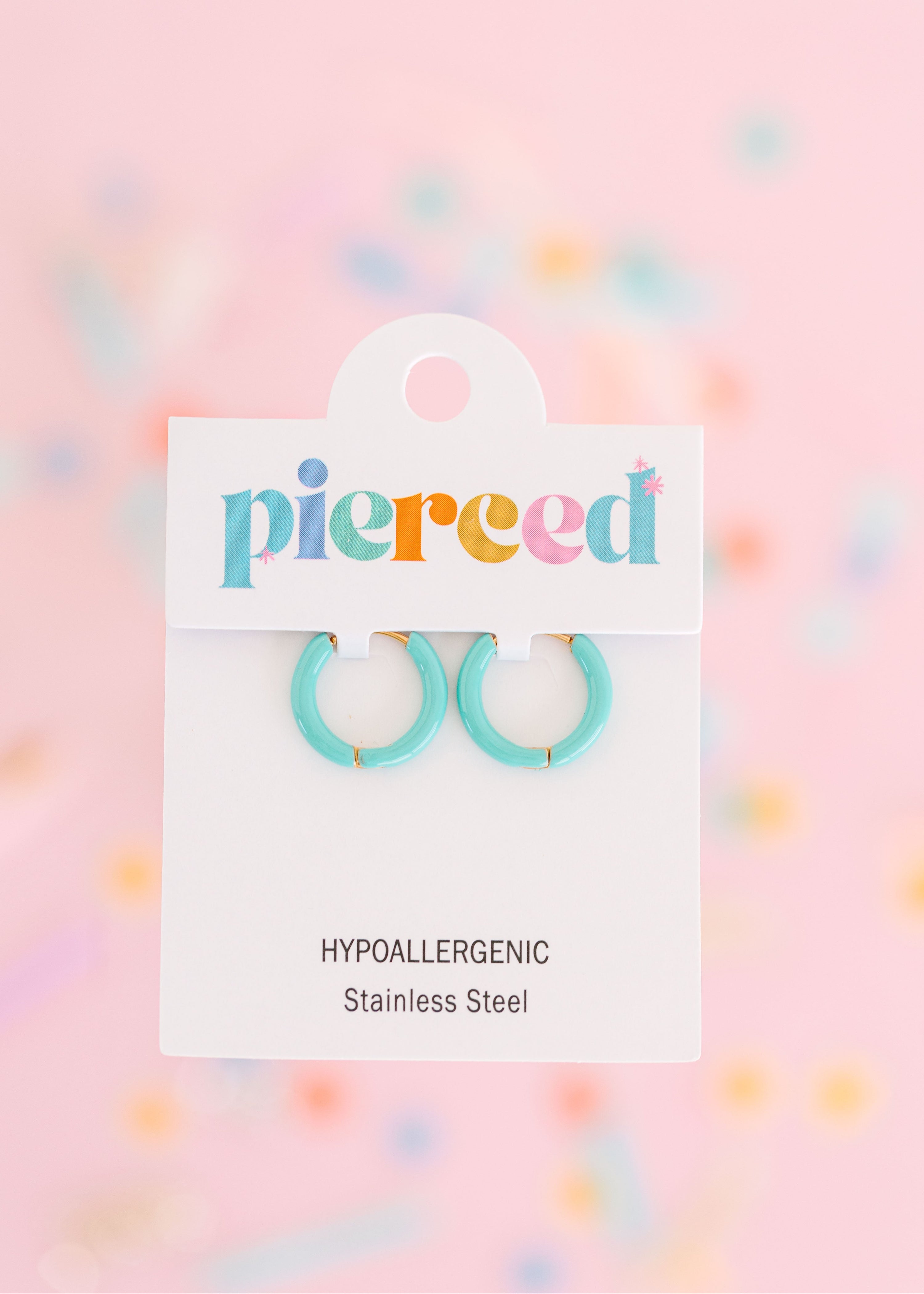Teal hoop earrings on their packaging card with a colorful blurred background