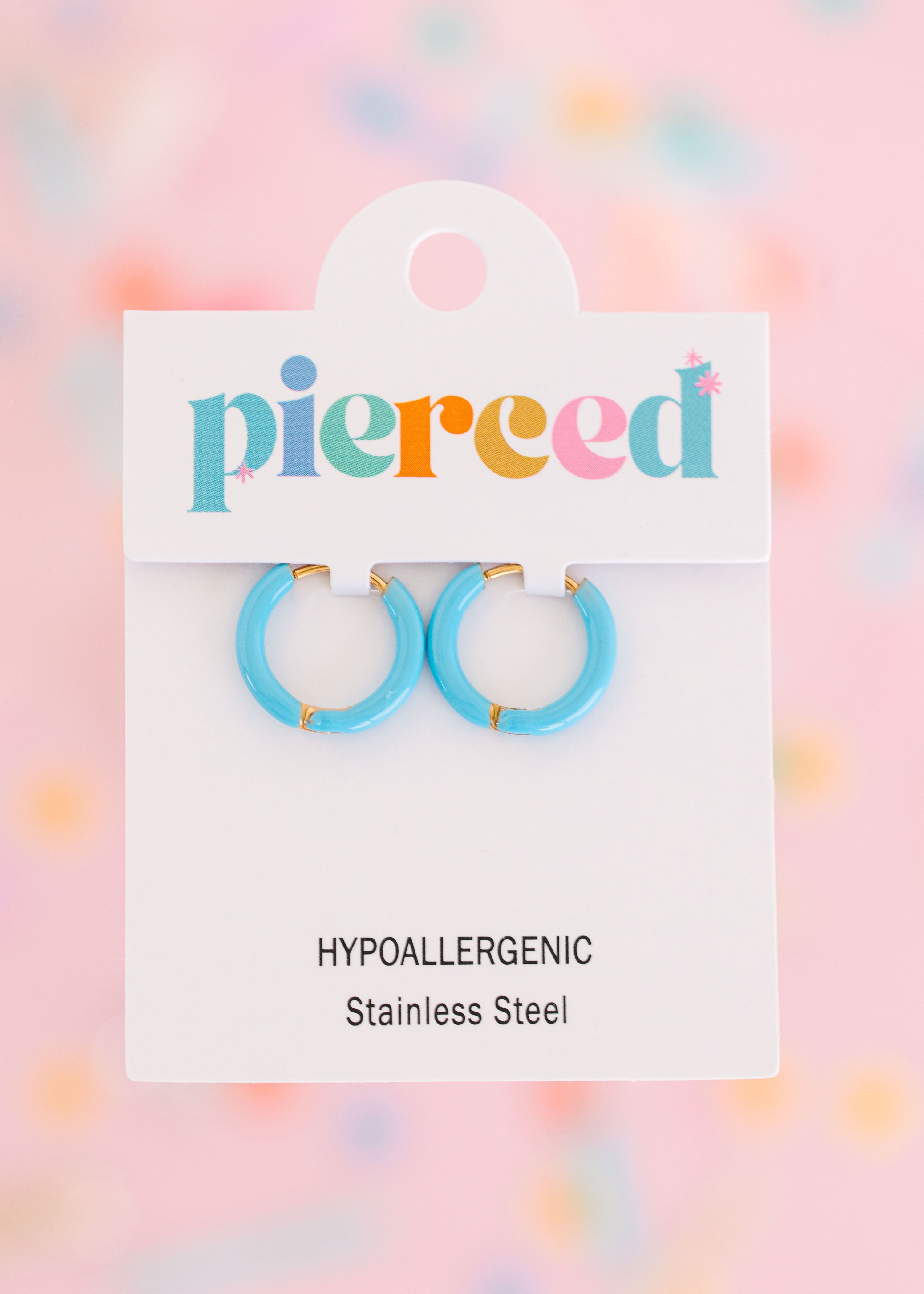 Blue hoop earrings on their packaging card with a colorful blurred background