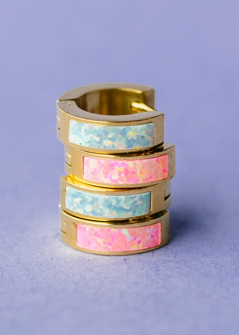 Stack of gold huggies with blue and pink opal inlay