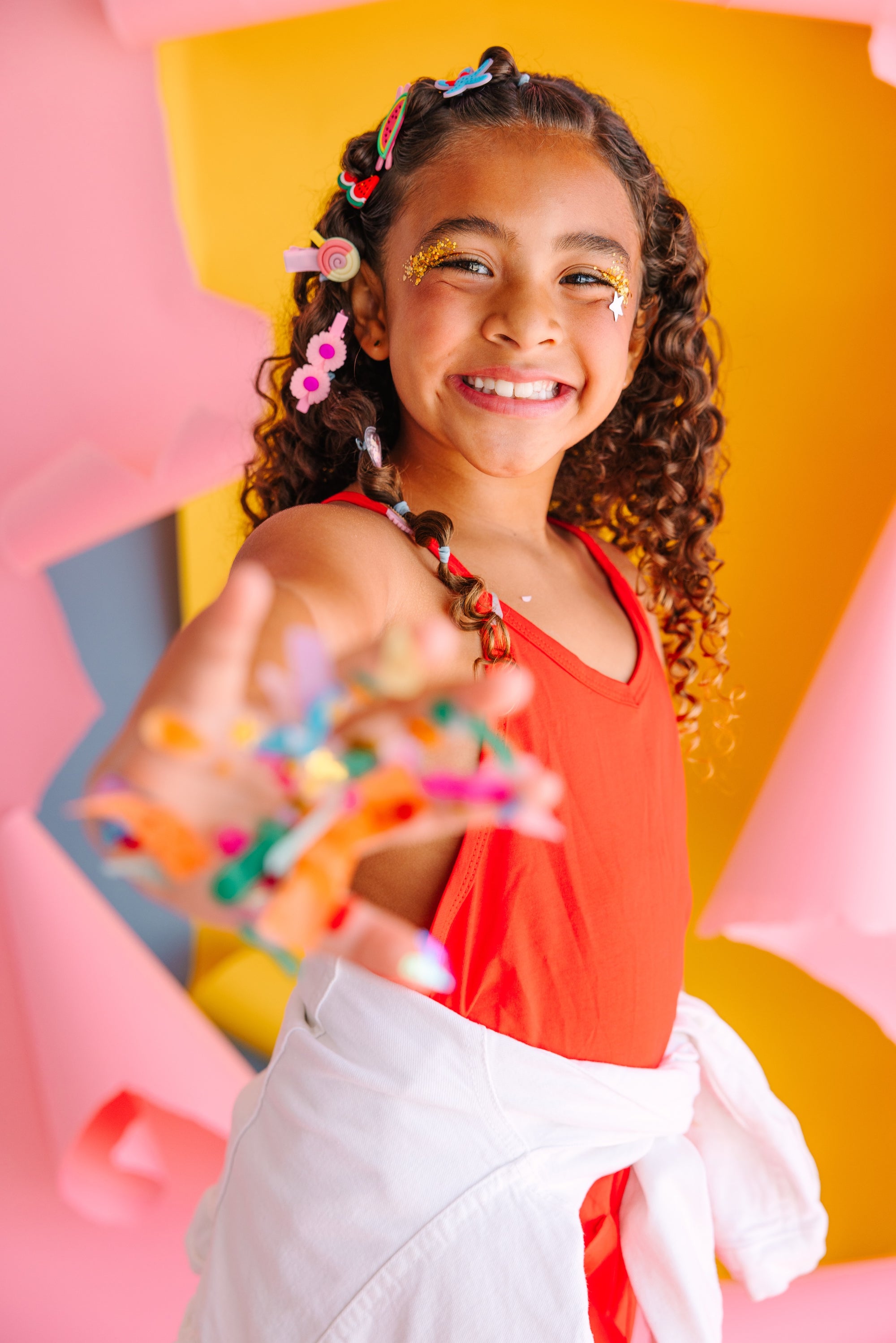 Young girl with colorful hair accessories and bracelets against a vibrant, abstract background