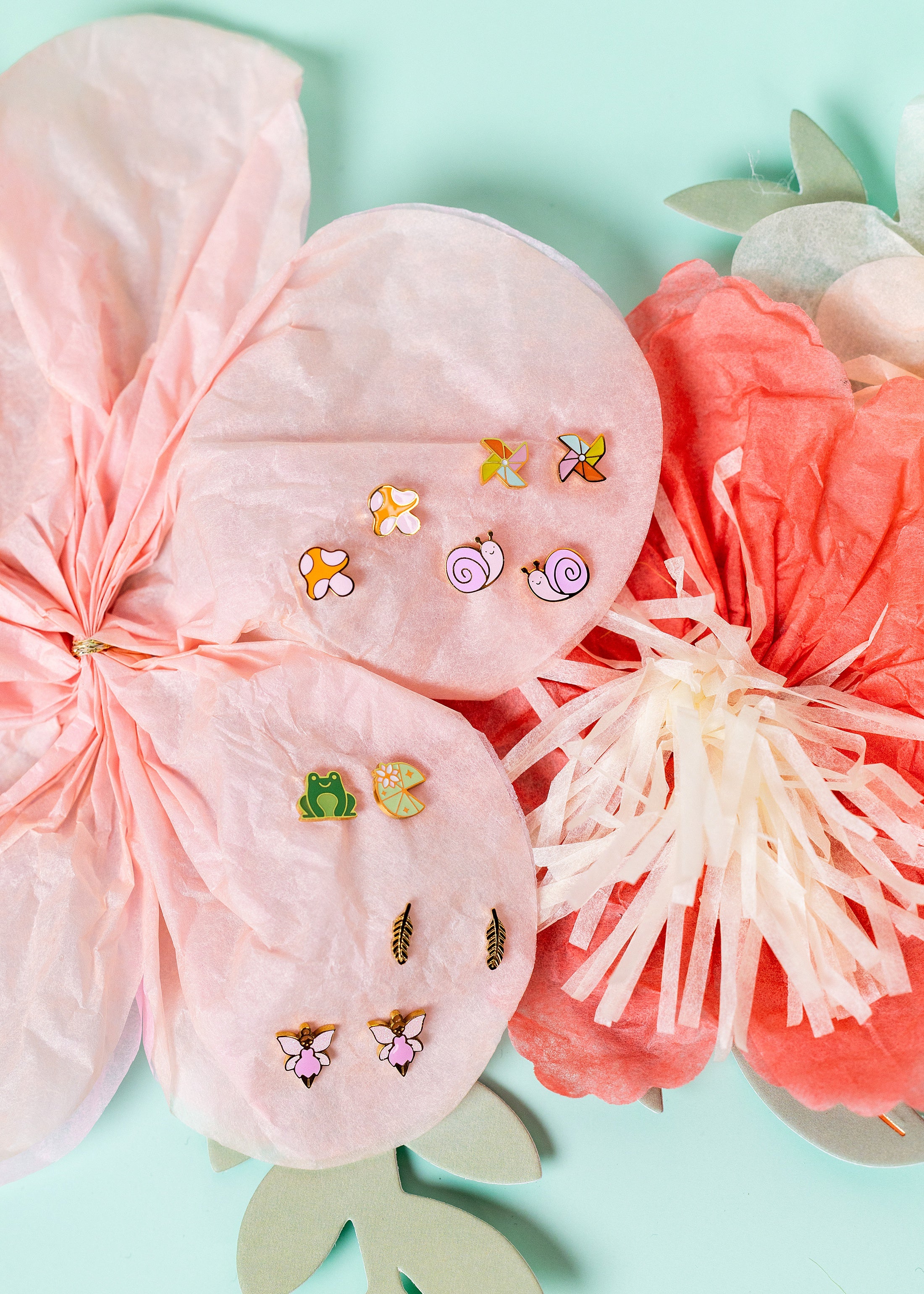 Set of butterfly-themed earrings on a pink floral cushion with a light blue background